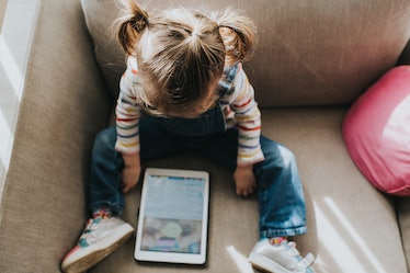 Little girl on a tablet computer in a bright and airy home. Space for copy.