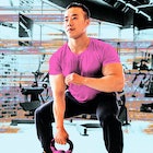 A man wearing a pink shirt using a dumbbells' at the gym while incorporating HIIT for beginners
