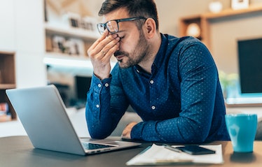 Man with glasses and laptop looking stressed