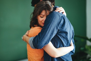 Man and woman hugging near green wall