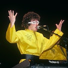 Weird Al Yankovic, wearing a yellow jumpsuit, singing the song "Dare To Be Stupid," a tribute to the...