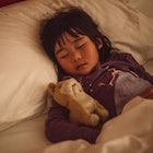 A child sleeping in bed with a stuffed animal.