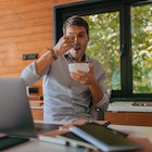 Portrait of young man enjoying eating while working at home.