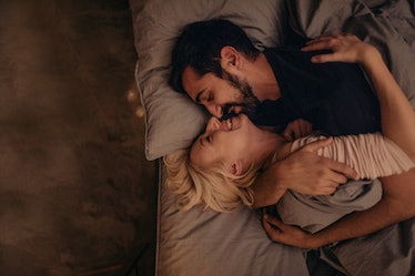 Man and woman in bed kissing and laughing