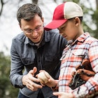 Adult man teaching young boy how to hold a baseball