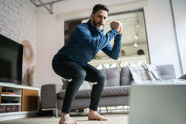 A man doing squats to lose belly fat while working out at home.