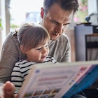 A dad reading a book with his young daughter.