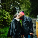 Happy couple kissing in the rain standing next camper van