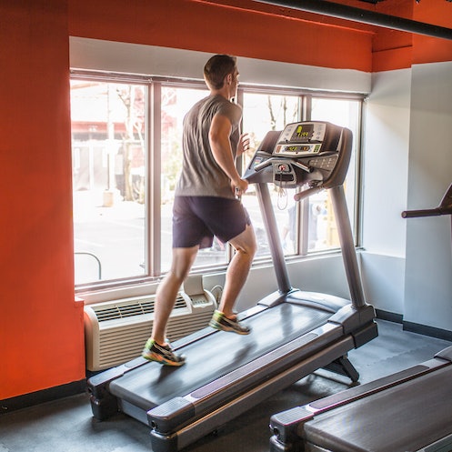 A man doing the 12-3-30 workout on a treadmill in a gym.