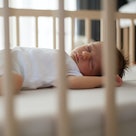 A baby sleeping in their crib.