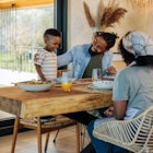 A young African American family is at home, bonding as they have lunch together in their modern dini...