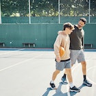 Father and son walking after playing a game of basketball. Maybe they're talking about gun safety ed...