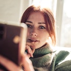 Woman with red hair reading text message