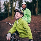 A boy and his dad mountain biking in the woods.