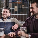 Confident, happy man sitting with friends around a table