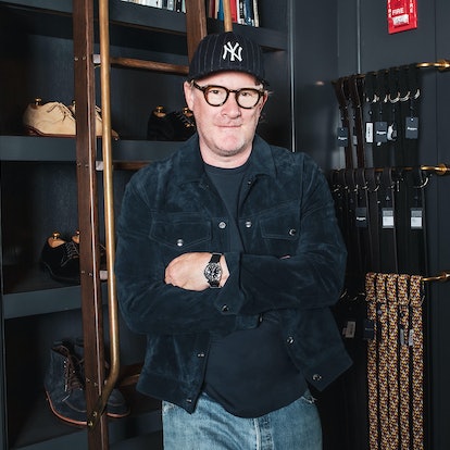 Todd Snyder wearing a new york yankees hat standing next to a rack full of belts and shelves of shoe...