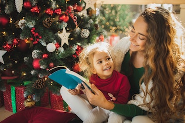 A mother and daughter reading a fairy tale next to a Christmas tree