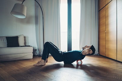 Young man using a foam roller on his back at home.