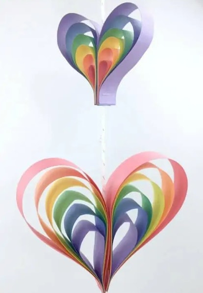 two colorful rainbow heart spin mobiles hanging from a white string in front of a white background
